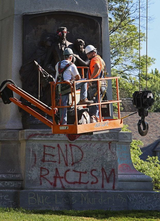 On Thursday, workers prepared the top of a 38-foot-tall granite monument to the Confederacy in St. Louis for removal with a crane. The bulk of the memorial might remain in place for weeks. (David Carson/St. Louis Post-Dispatch)